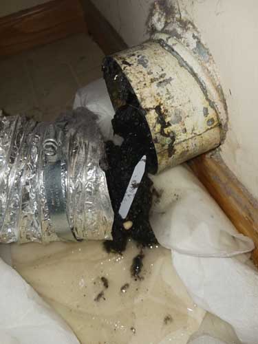 Damaged foil dryer vent hose disconnected and clogged with lint