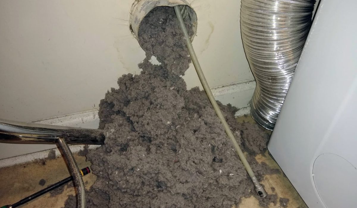 Heavy lint buildup being cleared from a clogged dryer vent line during service