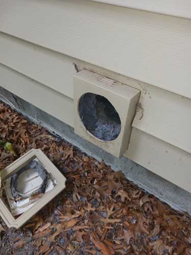 Exterior dryer vent cover removed showing lint buildup